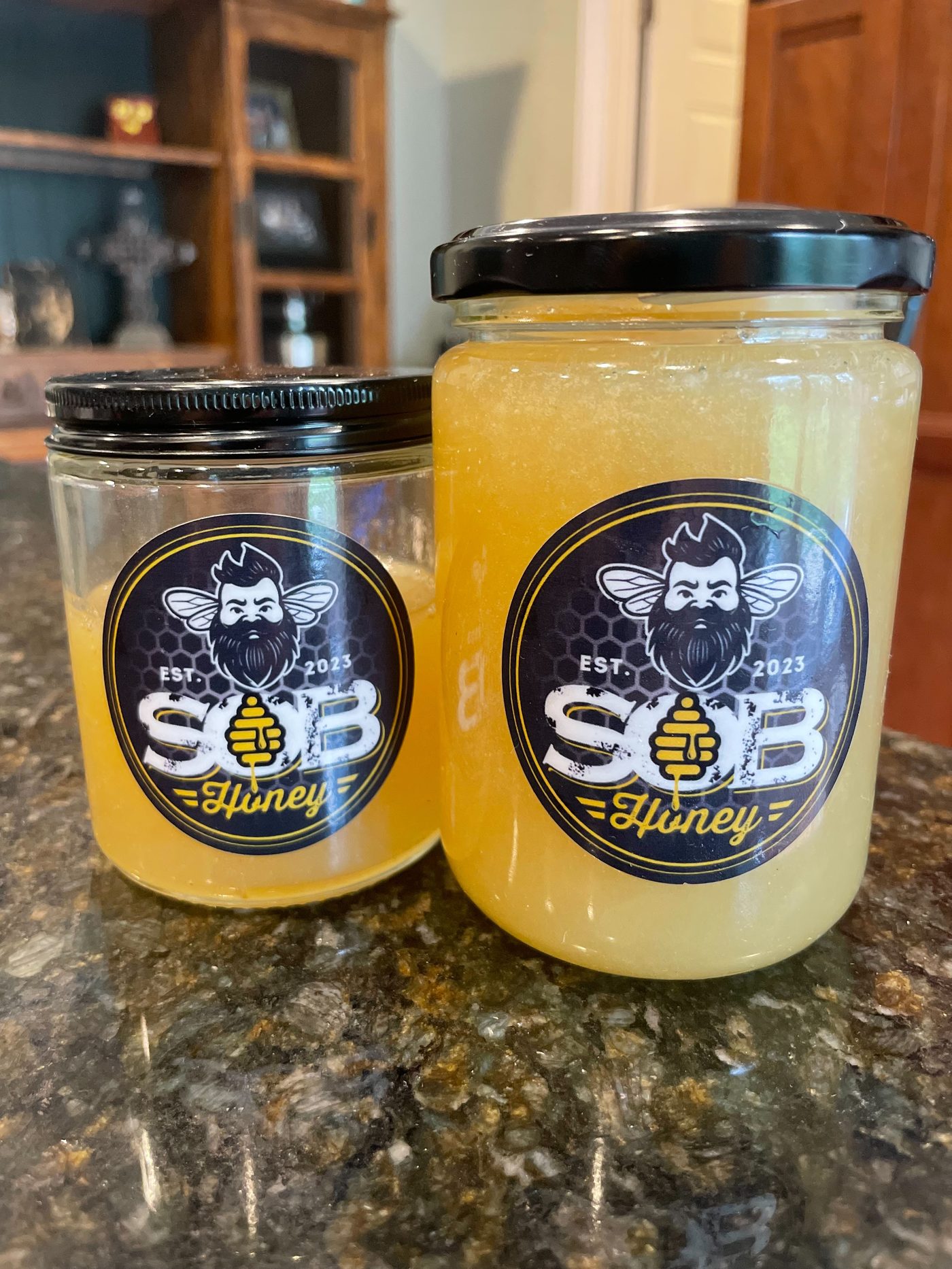 Two SOB Honey jars side by side — one liquid amber, one crystallized.